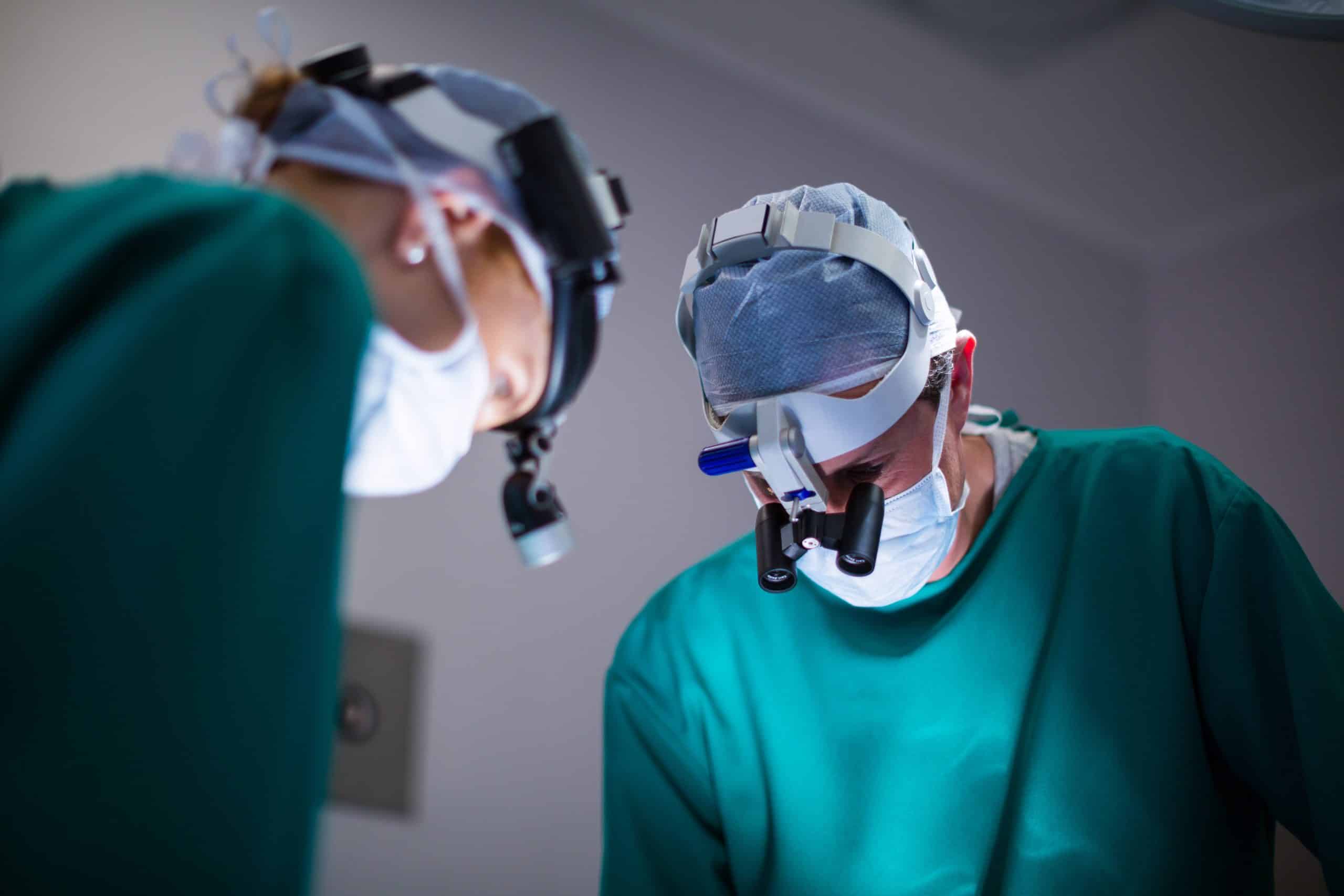surgeons wearing surgical loupes while performing operation min scaled
